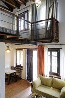 A loft-style room with a dining area, a sofa, and a window with curtains.