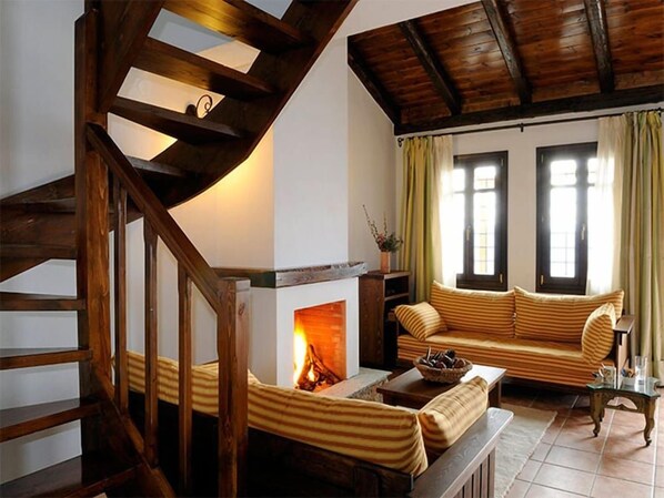 A living room with a fireplace, a wooden staircase, and a sofa. - Esperos (South Pelion)