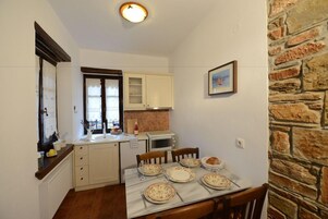 A compact kitchen with a dining table set for four, a microwave, and a window with curtains.