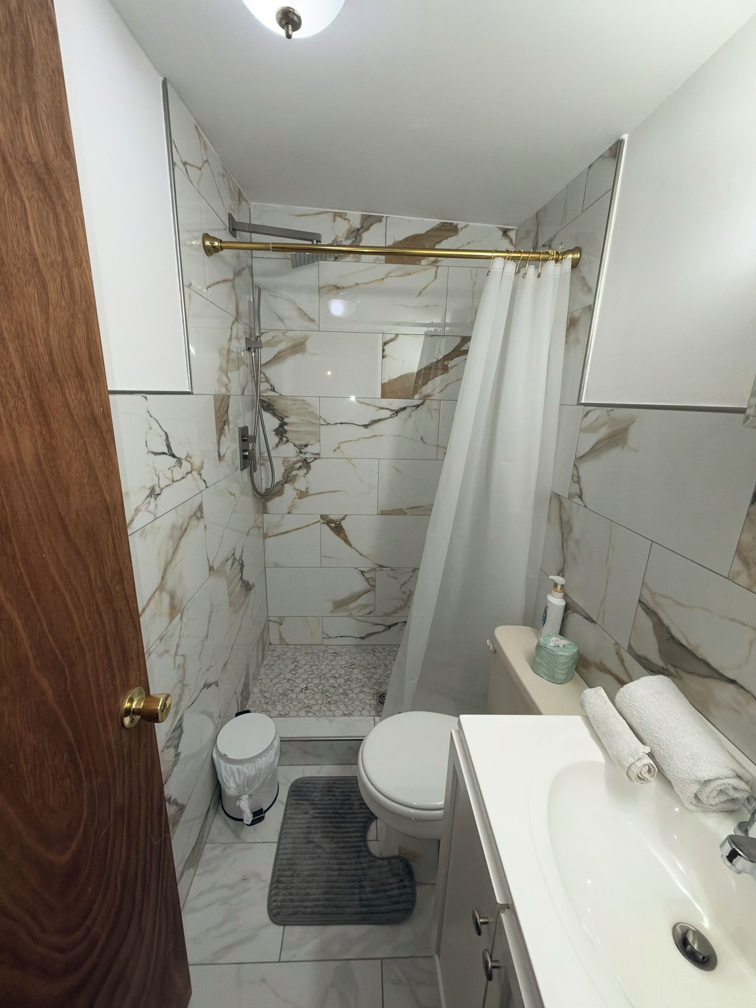Une salle de bain avec une douche, des toilettes, un lavabo et une serviette posée sur le comptoir.