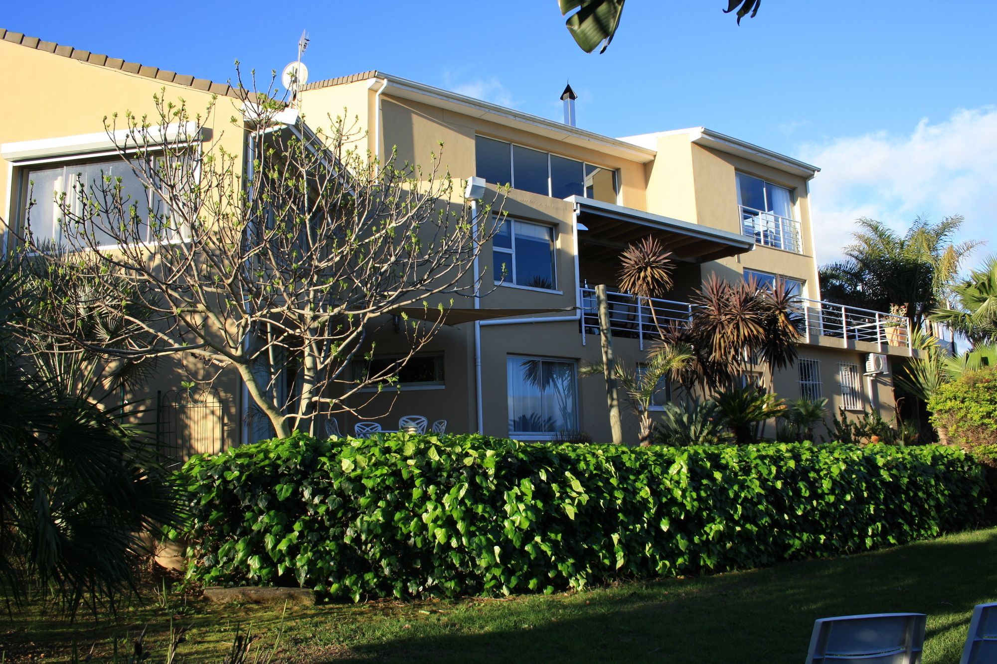 A multi-story residential building with a flat roof, large windows, and a balcony.