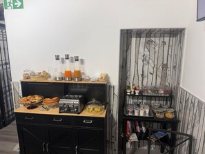 Uma mesa de pequeno-almoço com diversas opções de comida e uma máquina de café.