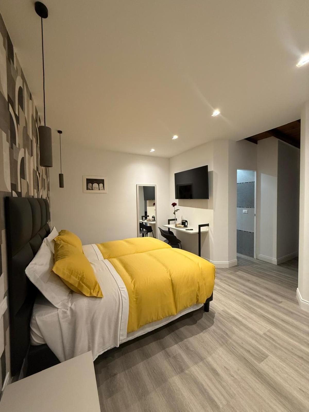 A modern bedroom with a large bed, a desk, and a television.