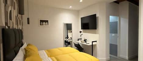 A modern bedroom with a large bed, a desk, and a television.