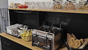 A buffet setup with various food items, a toaster, and condiments.