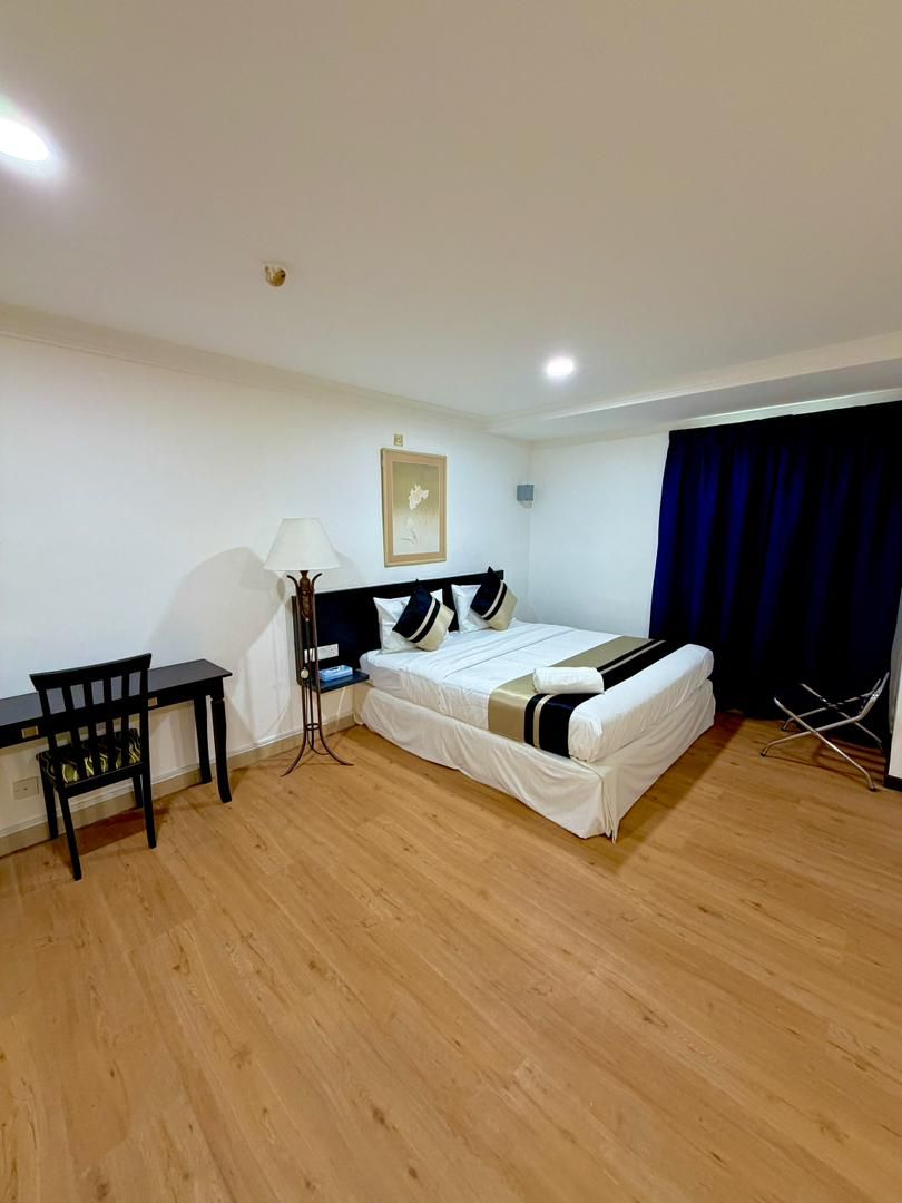 A room with a bed, a desk, a chair, a lamp, and a curtain.