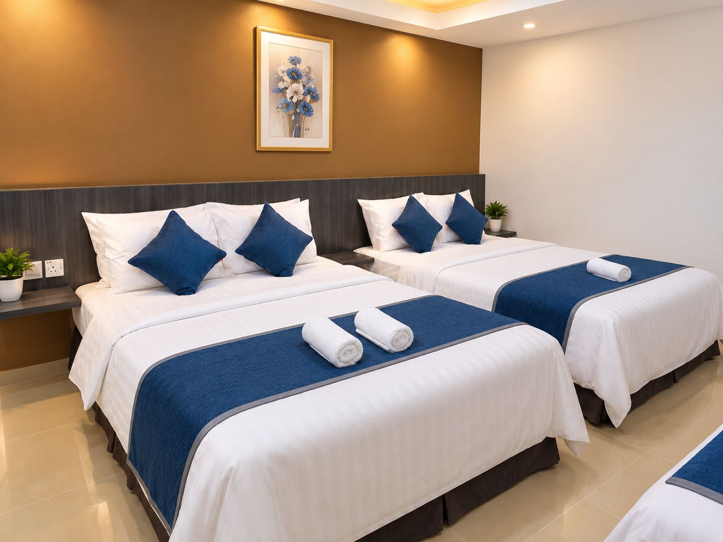 A hotel room with two beds, each with white bedding and blue accents, a headboard, and a framed artwork on the wall.