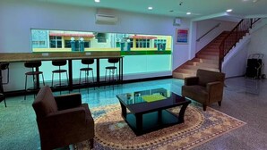 Un hall con zona de bar, asientos y una escalera.