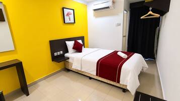 A hotel room with a bed, a bedside table, a hanging coat rack, and a picture on the wall.