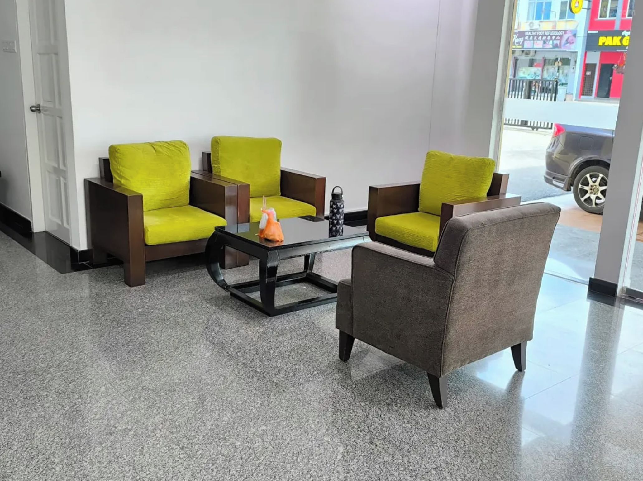 A reception area with a seating arrangement including two armchairs and a sofa, a coffee table, and a water bottle.