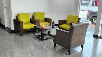 Zona de recepción con una disposición de asientos que incluye dos sillones, un sofá, una mesa de centro y una botella de agua.