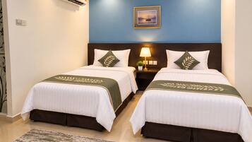 A hotel room with two beds, a nightstand with a lamp, a framed picture on the wall, and a patterned rug.