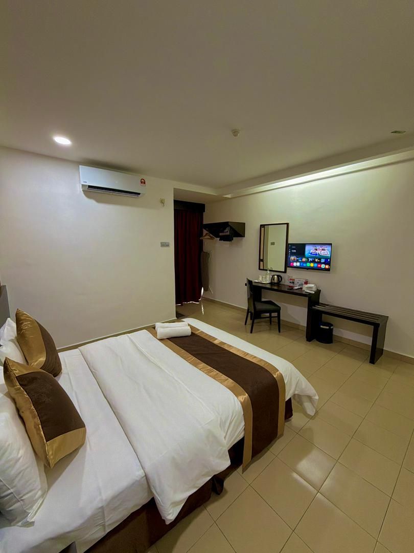 A hotel room with a bed, desk, chair, and television.