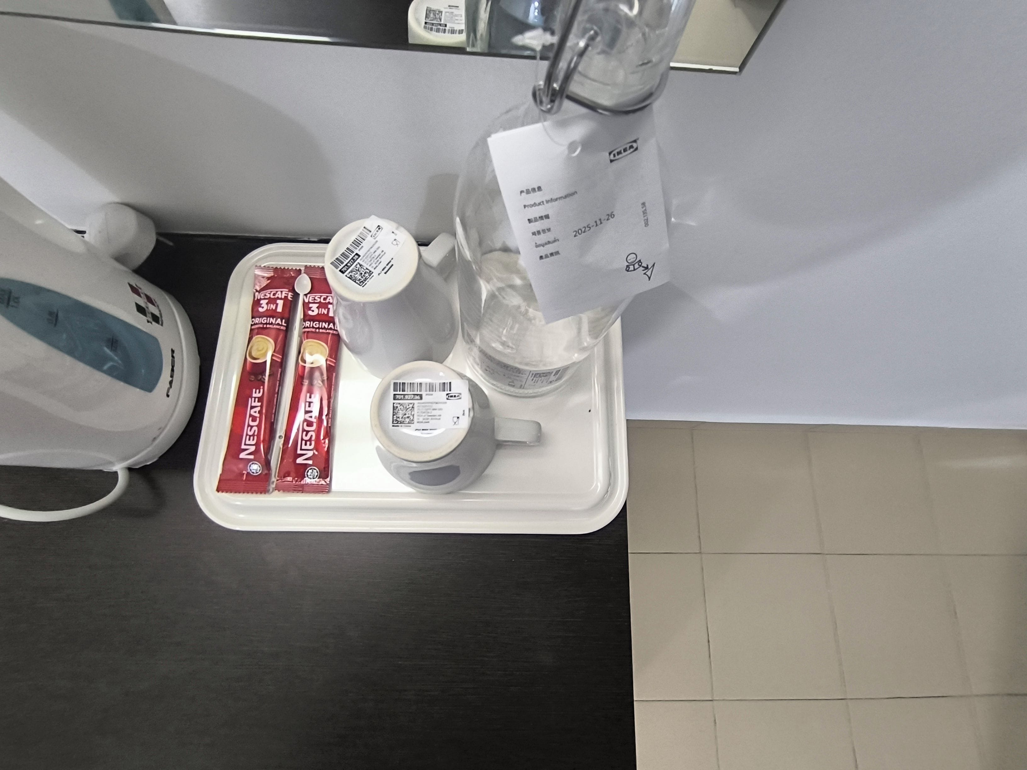 Tarjottimella on kahvinkeitin, vesipullo, muki ja kaksi pakettia Nescafe-kahvia.