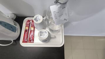 Una bandeja con cafetera, una botella de agua, una taza y dos sobres de café Nescafe.