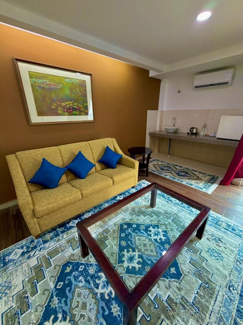 Una sala de estar con sofá, mesa de centro y un cuadro en la pared.