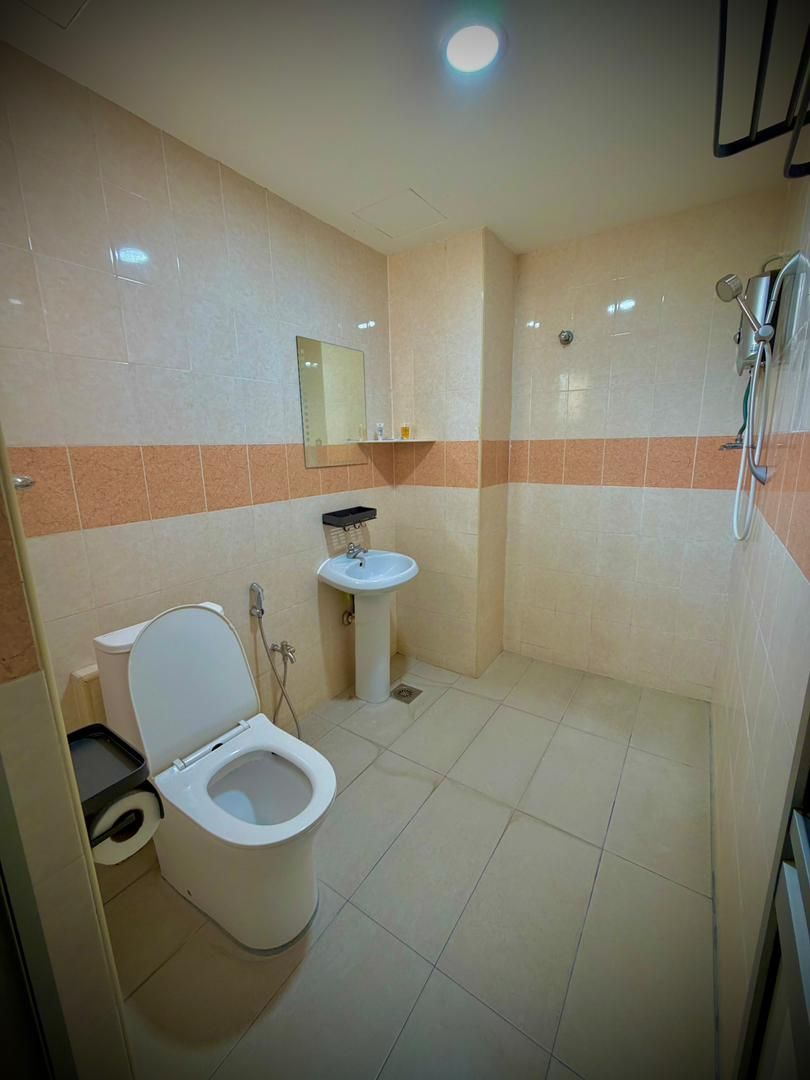 A small bathroom with a toilet, sink, and shower.