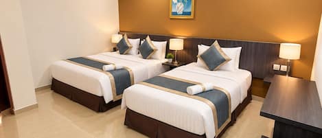 A hotel room with two beds, a nightstand, a desk, and a wall-mounted painting.
