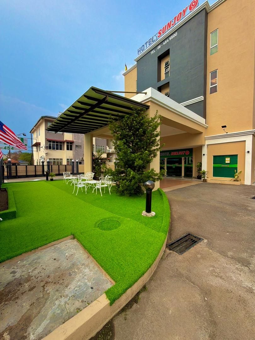 A hotel with a covered outdoor seating area, a well-maintained lawn, and a building with a modern design.