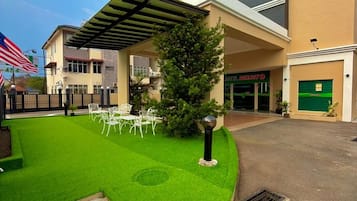 Un hotel con un área de estar al aire libre cubierta, césped bien cuidado y un edificio de diseño moderno.
