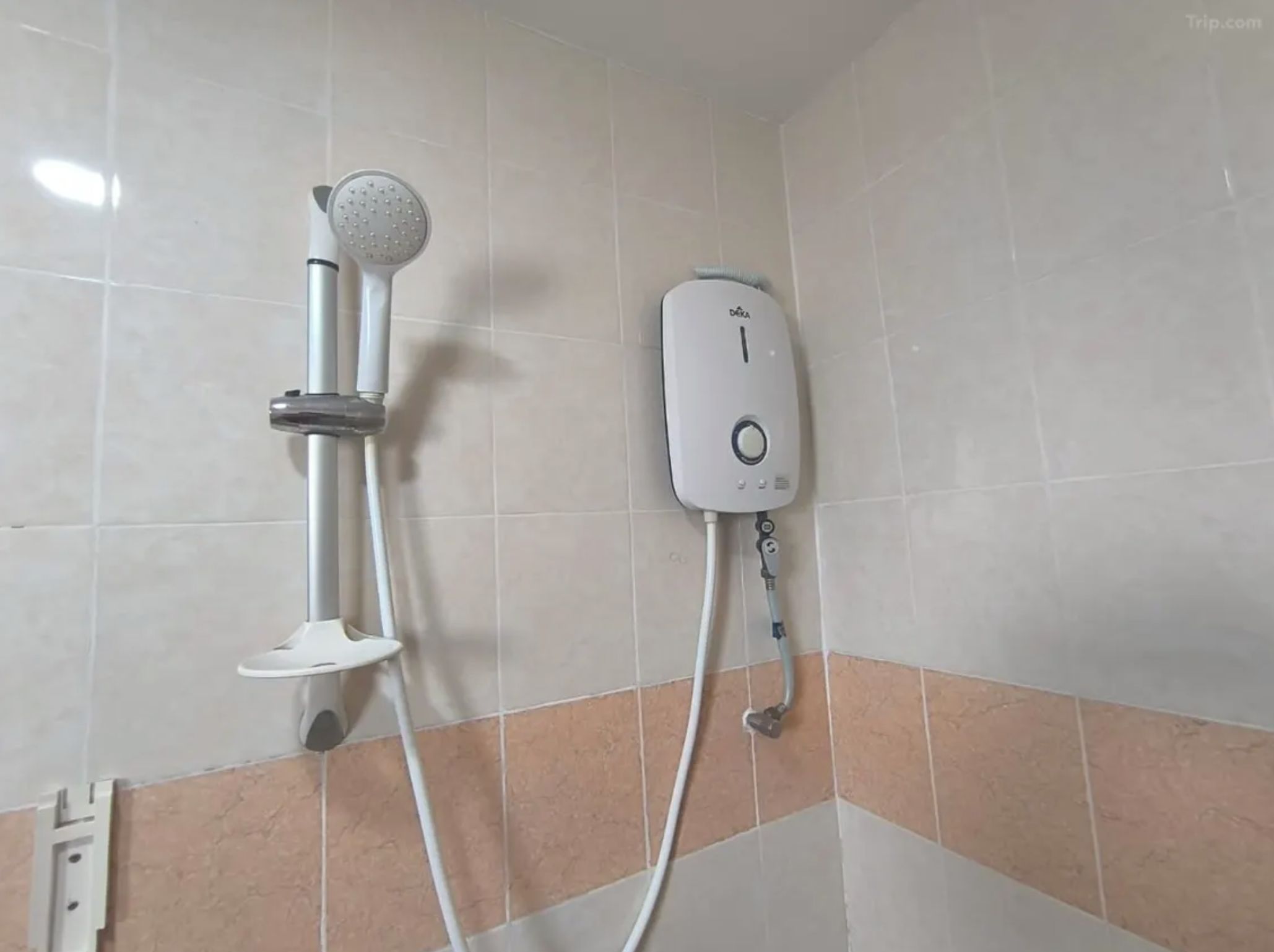 A bathroom with a shower unit and a handheld showerhead mounted on the wall.