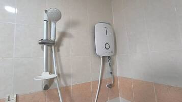 A bathroom with a shower unit and a handheld showerhead mounted on the wall.