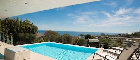 A rooftop pool with a clear view of the ocean and surrounding buildings.