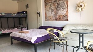 Una habitació amb un llit, una cadira, una taula petita, un sofà i un mapa penjat a la paret.