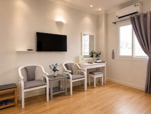 Een moderne woonkamer met een flatscreen televisie, een bureau en twee stoelen.
