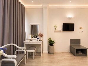 A modern hotel room with a desk, chair, television, and a shoe storage unit. - KAS Elegance Hotel (Ben Thanh Ward)