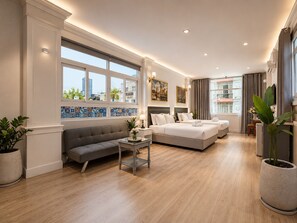 A modern hotel room with a sofa, a bed, a small table, and a potted plant. - KAS Elegance Hotel (Ben Thanh Ward)