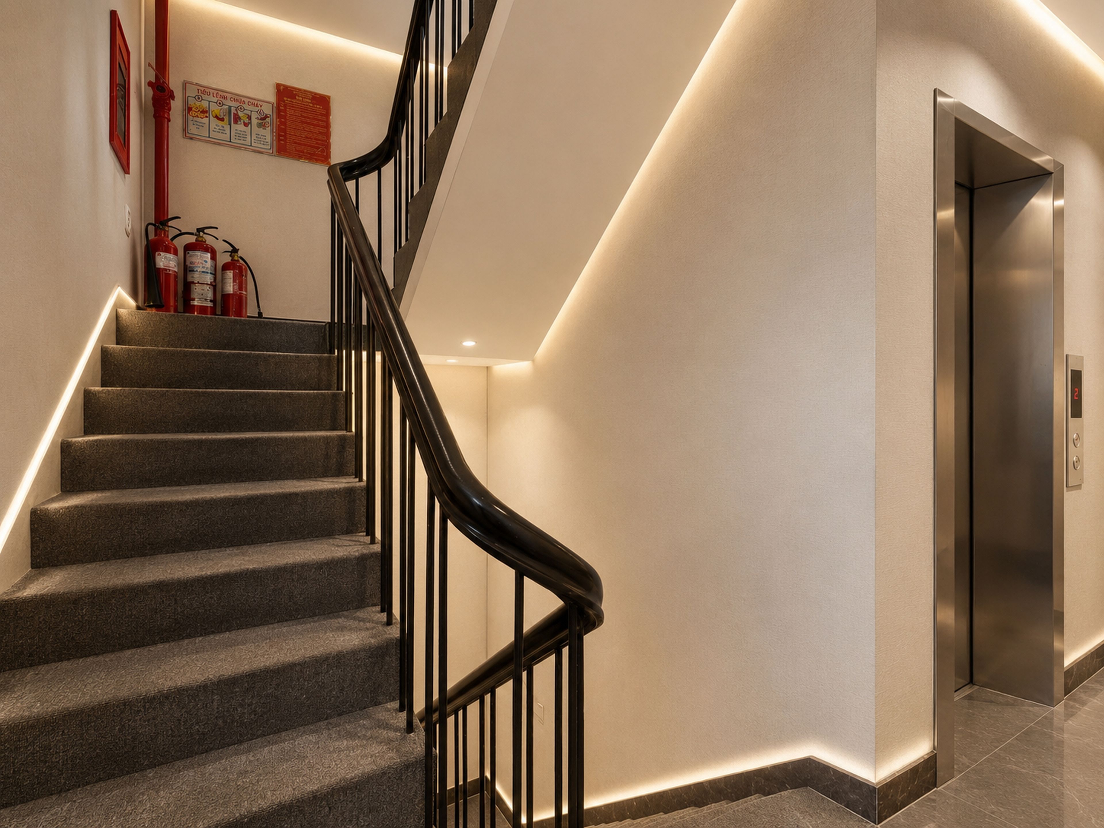 A modern staircase with a black railing, a fire extinguisher, and an elevator.