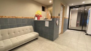 A reception area with a sofa, a reception desk, and a wall-mounted sign. - Kyogura Tofukuji (Kyoto)