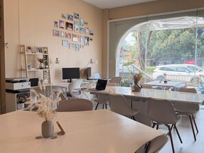 A modern office space with a large desk, computer, and a view of the street through a large window.