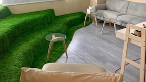 A modern living room with a sectional sofa, a small round table, and a green artificial grass area.