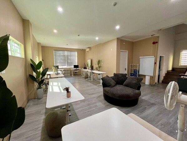 A modern office space with a meeting table, a sofa, and a fan.
