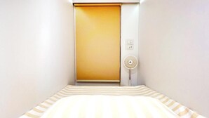 A room with a bed, a closed door, and a wall-mounted fan.