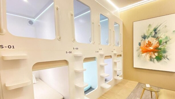 A hotel room with a bunk bed, a wall-mounted shelf unit, and a painting.