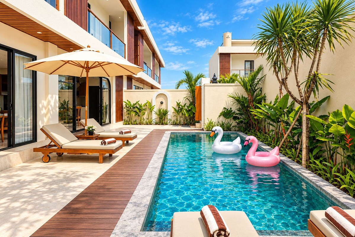 A swimming pool with lounge chairs and swan floats, surrounded by tropical plants and a modern building.