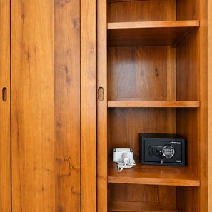 Een houten kast met een zwarte kluis en een wit apparaat op het onderste plankje.