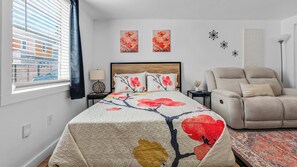 A bedroom with a bed, a chair, a lamp, and artwork on the walls. - Chic 1BR Loft w/ Backyard near Pearl & Downtown (San Antonio)