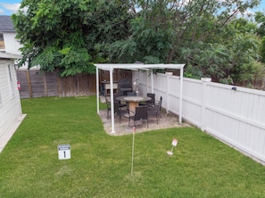A backyard with a patio table and chairs, a white fence, and a 'Reserved Parking 1' sign. - Chic 1BR Loft w/ Backyard near Pearl & Downtown (San Antonio)