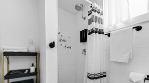 Een moderne badkamer met een douche, een handdoekhouder en een plank met toiletartikelen.