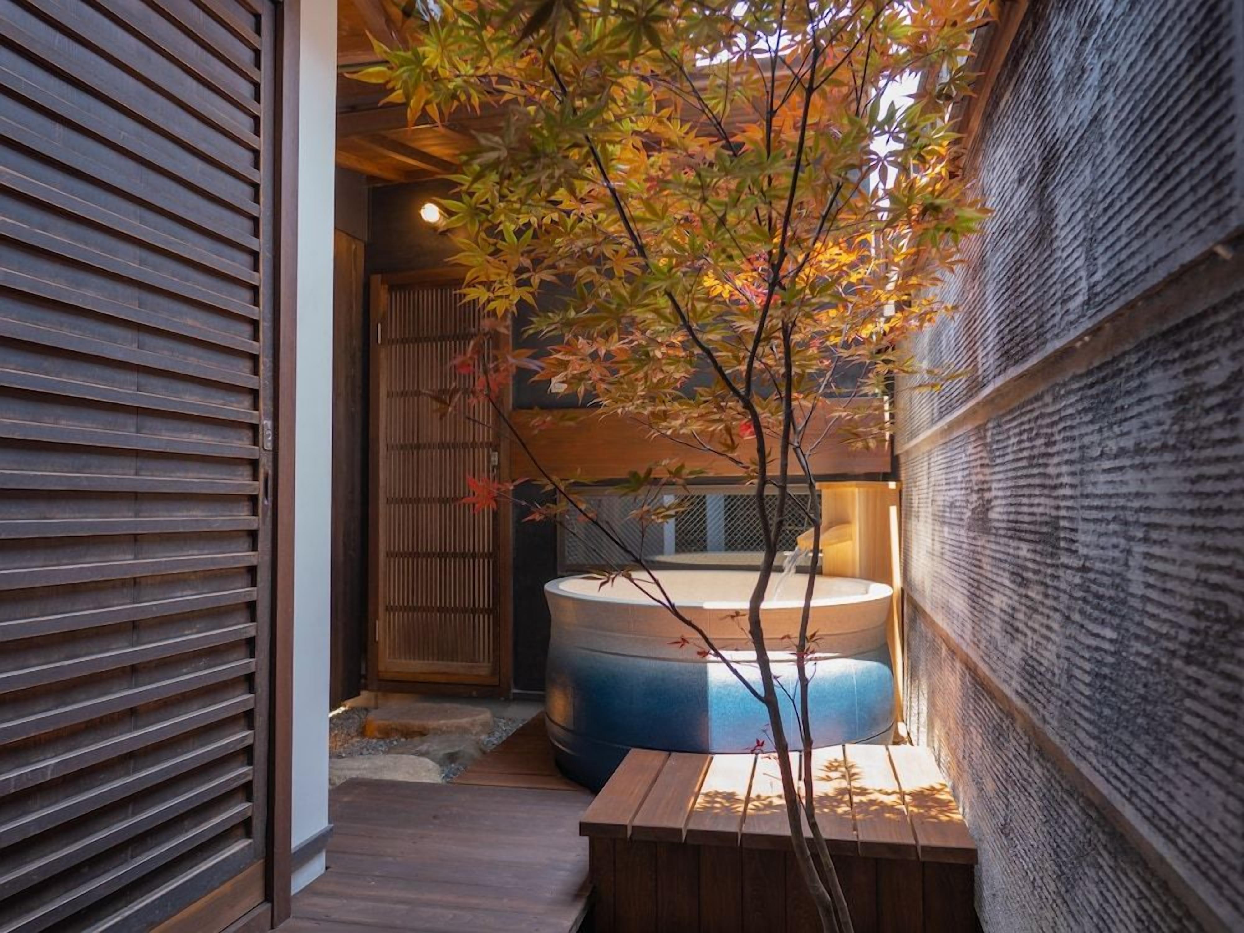 A traditional Japanese-style room with tatami flooring, a wooden sliding door, and a hot tub.