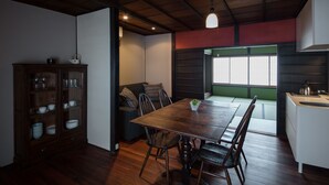 A dining area with a wooden table and chairs, a cabinet with glass doors, and a view through a window. - Shimoza-an (Kyoto)