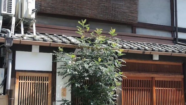 A traditional building with a tiled roof, wooden doors, and air conditioning units. - Shimoza-an (Kyoto)