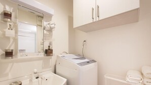 A bathroom with a sink, mirror, towel rack, and a white washing machine. - Hotel Stay Sakura Nipponbashi (Osaka)