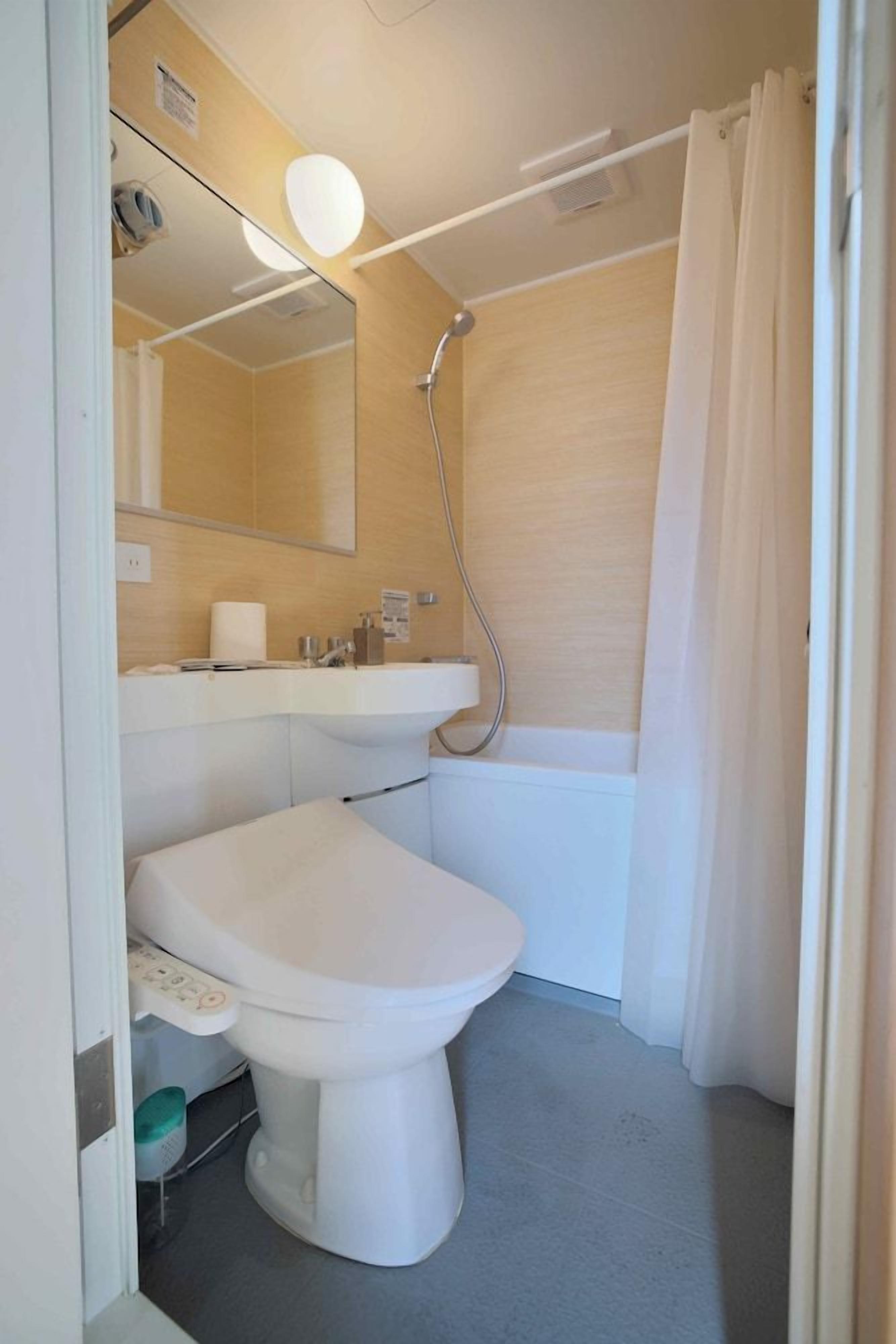 A bathroom with a toilet, sink, and shower.