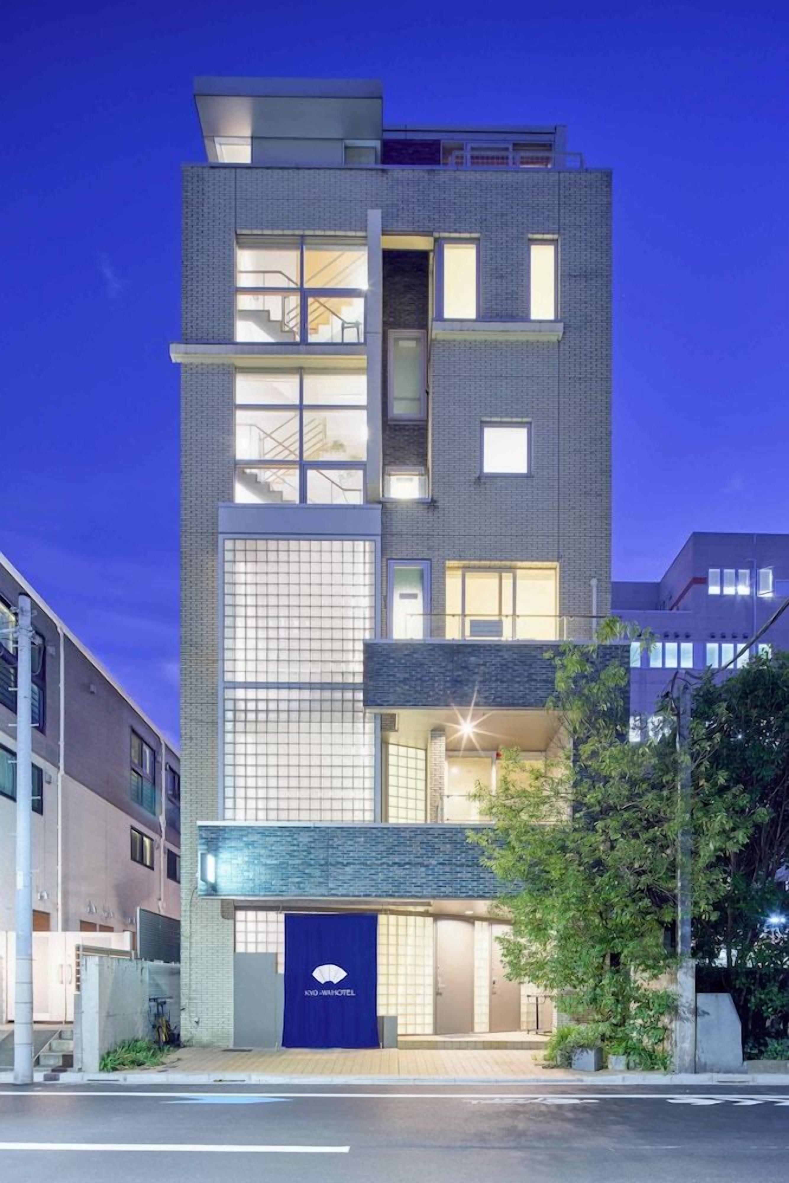 A multi-story hotel with a modern design, featuring a prominent entrance with a blue awning and a visible logo.