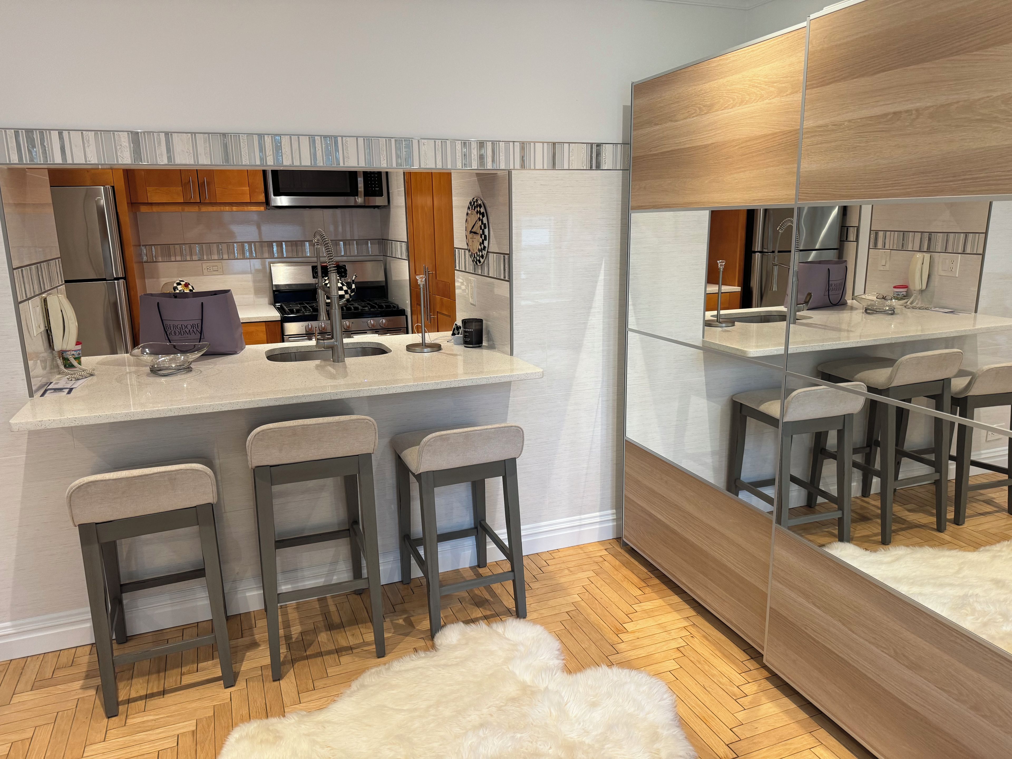 A modern kitchen with a central island, bar stools, and a large mirror.